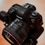 Close-up of a Canon DSLR camera with a lens mounted on a tripod.